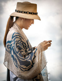 Stylish woman texting against sky