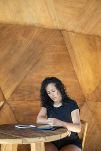 Woman using a digital tablet while sitting at a table.