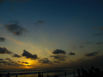 Silhouette people on beach against sky during sunset