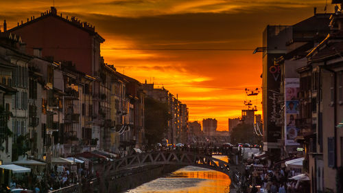 Street amidst buildings against sky during sunset