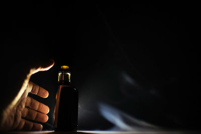 Close-up of hand holding candle against black background