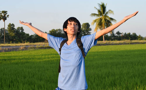 Young man with arms outstretched standing on field