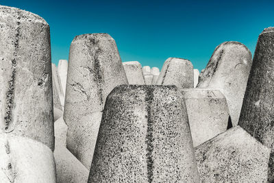 Close-up of tetrapods against clear blue sky during sunny day