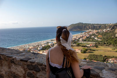 Rear view of woman looking at sea shore against sky