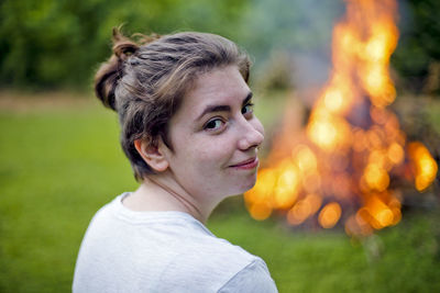 Close-up portrait of young woman by campfire