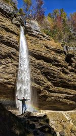 Low angle view of man standing against waterfall