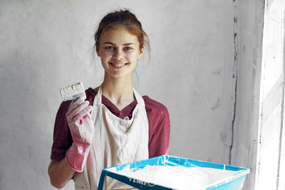 Portrait of young woman standing against wall