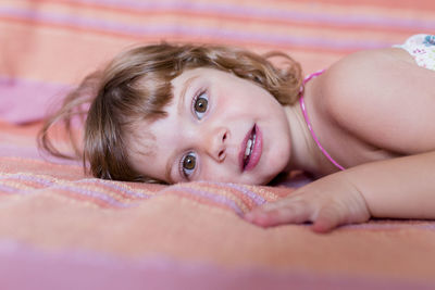 Portrait of smiling cute girl lying on sofa