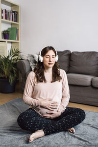 Young woman sitting on sofa at home