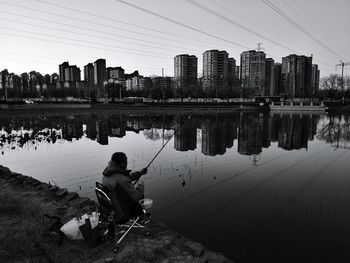 Man fishing at lake in city