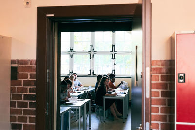 Students learning language in classroom seen through doorway