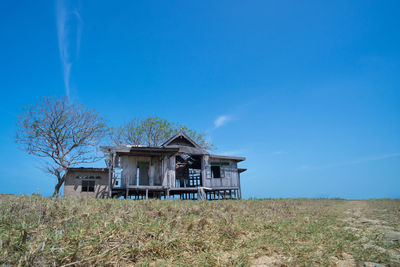 Abandoned house on field against blue sky