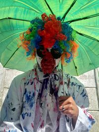 Portrait of person holding multi colored umbrella