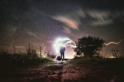 Woman on illuminated field against sky at night