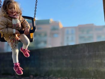 Girl in playground against sky