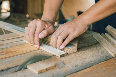 Carpenter is using a circular saw to cut wood to construct a storage box on desk  at his factory