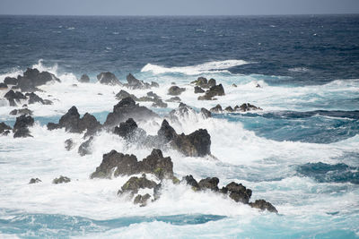 Scenic view of rocks in sea against sky