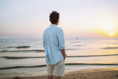 Androgynous woman looking at sea on sunset