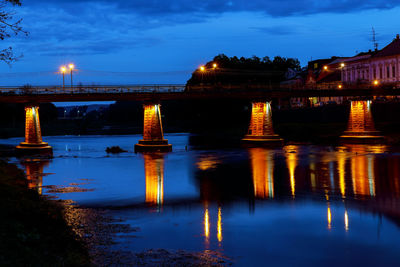 Illuminated bridge over river at night