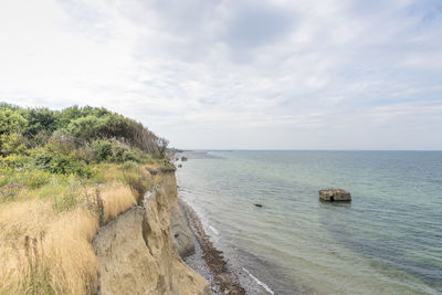 German baltic sea coast with sand dunes, grass, water and blue sky