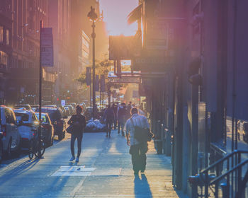 Rear view of people walking on city street