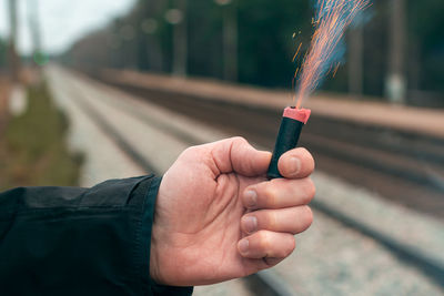 Close-up of hand holding railroad tracks