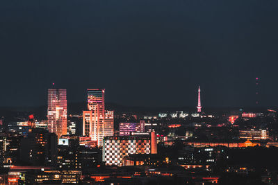 Illuminated buildings in city against sky at night