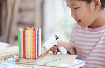 Close-up of girl making craft product on table