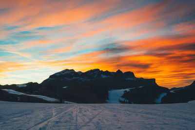 Scenic view of snow covered mountains against orange sky