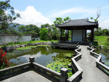 Gazebo in park by lake against sky