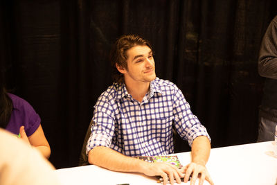 Young man looking away while sitting on table