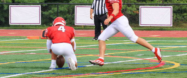 Side view of a football kicker in the process of kicking a field goal during a game.