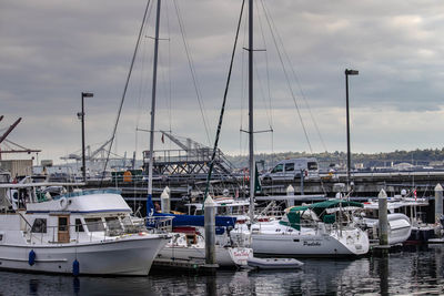 Sailboats moored at harbor against sky