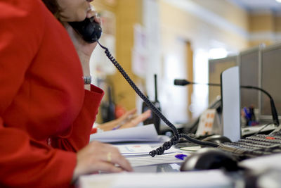 Midsection of woman talking over phone in office