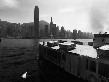 View of city at waterfront against cloudy sky