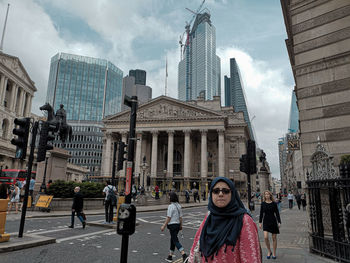 People on modern buildings in city against sky