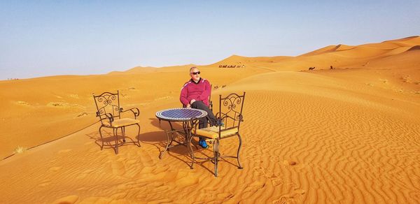 Man sitting on chair at desert