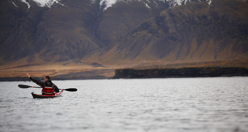 Mature man steering his sea kayak through calm waters around reykjavik