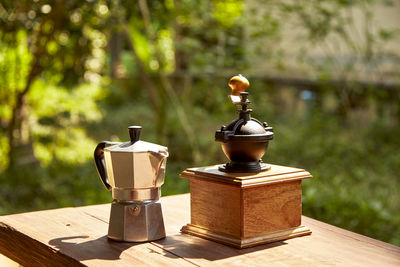 Close-up of coffee maker and grinder on table in park