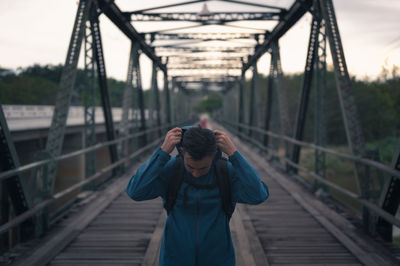 Young man backpacker walking cross the bridge and wearing hoodie  , freedom and recreation concept
