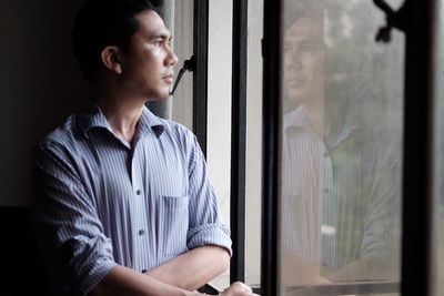 Thoughtful man looking through glass window