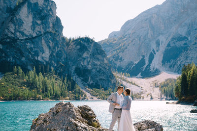 Rear view of couple standing on mountain against sky