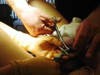 Cropped hands of surgeons with patient in operating room