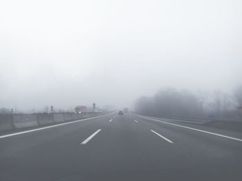 Empty country road against clear sky in foggy weather