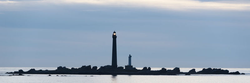 Lighthouse in sea against sky