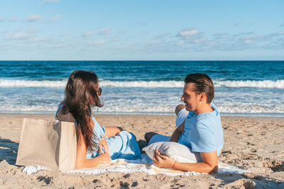 Side view of woman sitting at beach