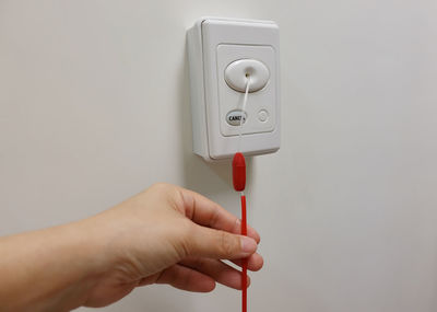 Close-up of hand holding electric lamp against wall