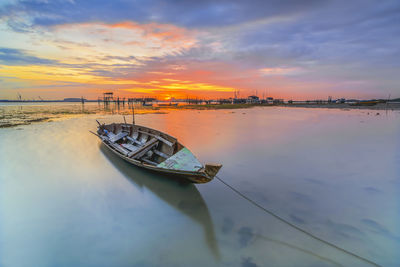 Boat moored on sea against sky during sunset