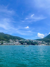 Scenic view of sea by townscape against sky