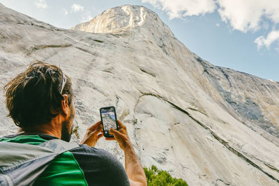 Young man taking picture of el capitan mountain in yosemite park.